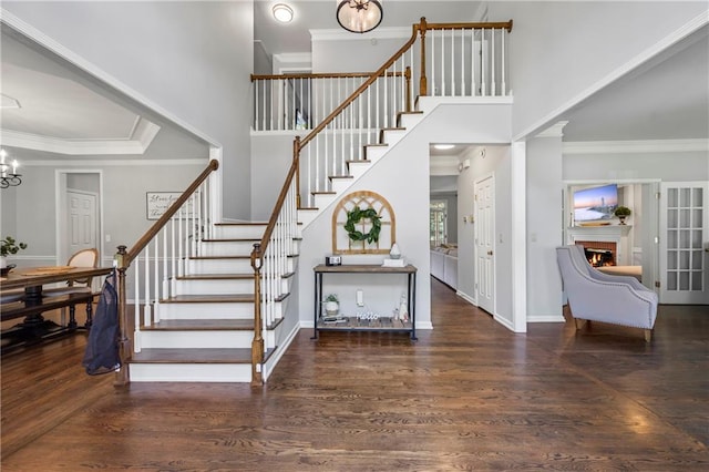 2500 Ashbourne Dr, Lawrenceville, GA 30043 - stairs with wood finished floors, a chandelier, a warm lit fireplace, a high ceiling, and ornamental molding