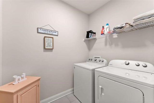 laundry area featuring baseboards, independent washer and dryer, light tile patterned flooring, and cabinet space