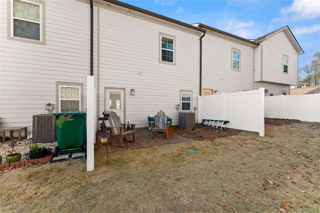 rear view of property featuring fence and central AC