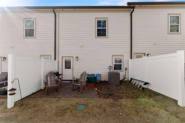 back of property with a patio area, fence, central AC, and a lawn
