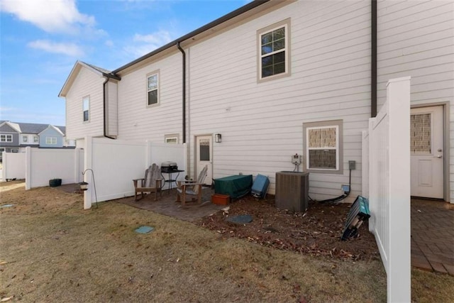 back of property with central AC unit, fence, and a patio