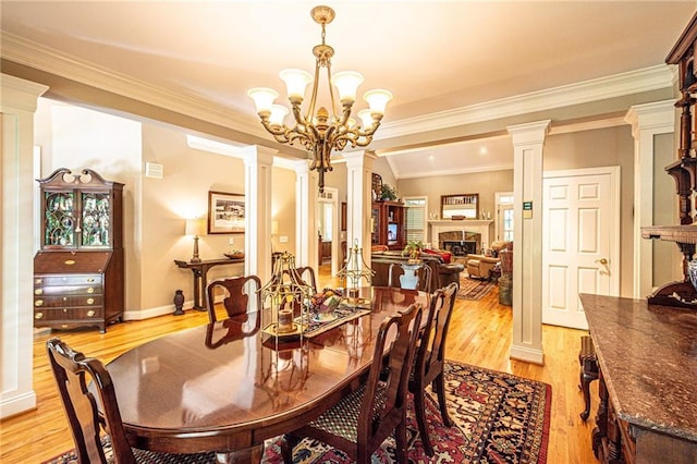 6369 Timber Creek Trl, Dahlonega, GA 30533 - dining space featuring decorative columns, light wood-style floors, ornamental molding, a fireplace, and a chandelier