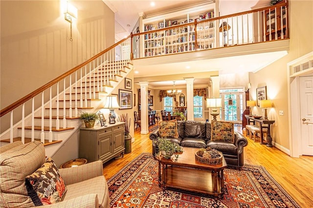 6369 Timber Creek Trl, Dahlonega, GA 30533 - living area featuring decorative columns, light wood-style floors, crown molding, a high ceiling, and stairs