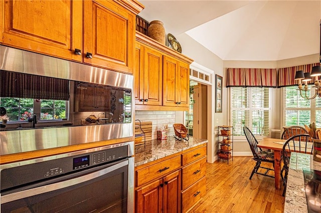 6369 Timber Creek Trl, Dahlonega, GA 30533 - kitchen with stainless steel appliances, light wood-style flooring, brown cabinetry, light stone countertops, and tasteful backsplash