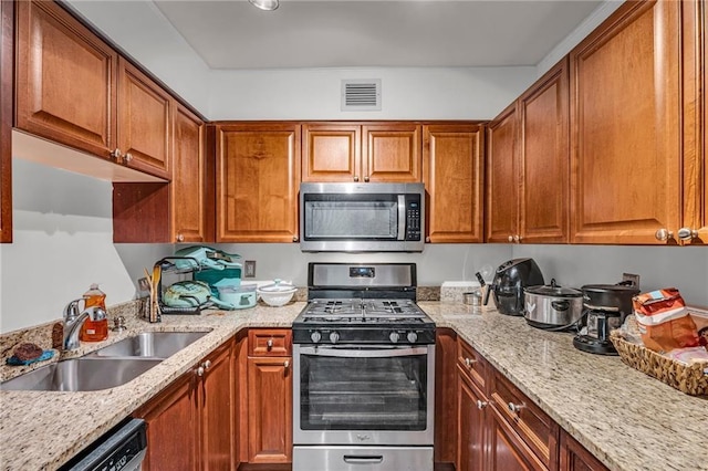 kitchen featuring a sink, light stone counters, visible vents, and stainless steel appliances