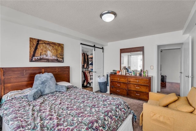 bedroom featuring a barn door, a textured ceiling, a closet, and carpet