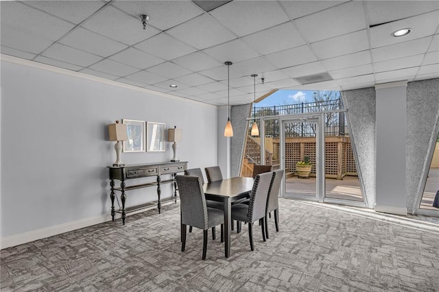 dining area with a drop ceiling, baseboards, ornamental molding, and carpet flooring