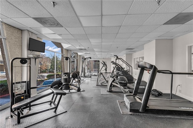 exercise room featuring a drop ceiling and baseboards