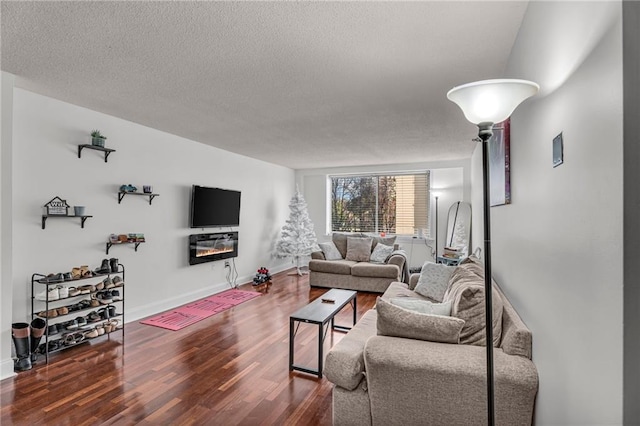living area featuring a glass covered fireplace, wood finished floors, baseboards, and a textured ceiling