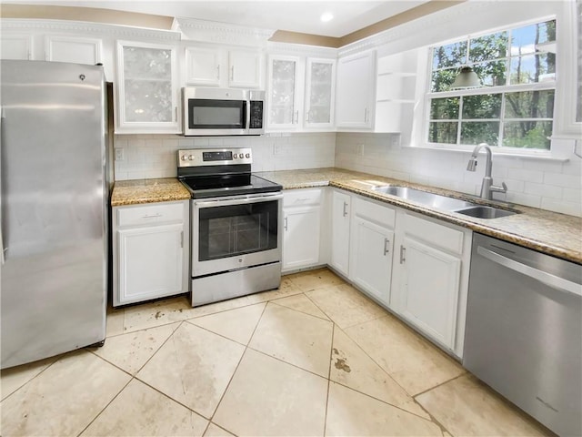 kitchen with sink, stainless steel appliances, tasteful backsplash, white cabinets, and light tile patterned flooring