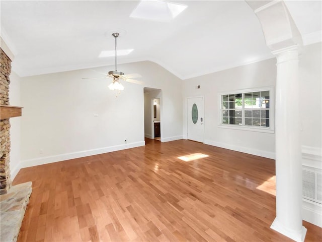 unfurnished living room featuring hardwood / wood-style flooring, a stone fireplace, ceiling fan, and decorative columns