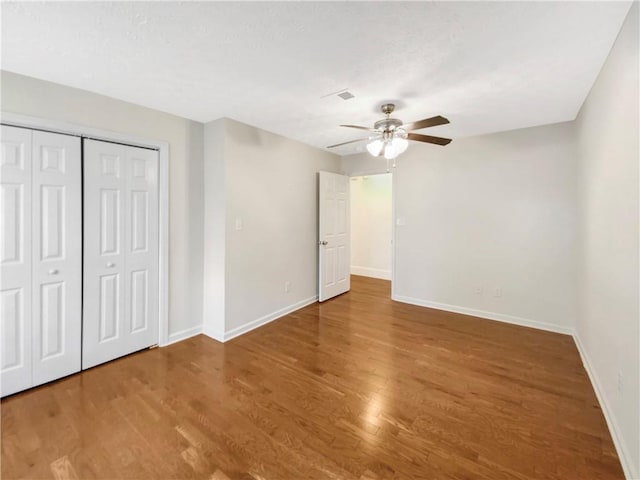 unfurnished bedroom with ceiling fan, a closet, and hardwood / wood-style flooring