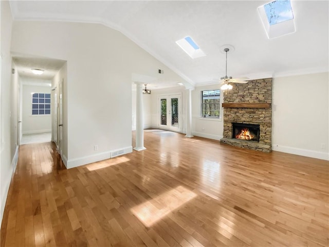 unfurnished living room featuring ceiling fan, lofted ceiling with skylight, hardwood / wood-style flooring, a fireplace, and ornamental molding