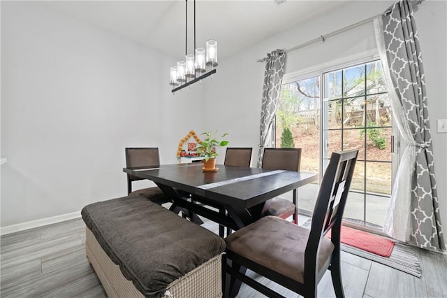 dining area featuring an inviting chandelier, baseboards, and light wood-type flooring