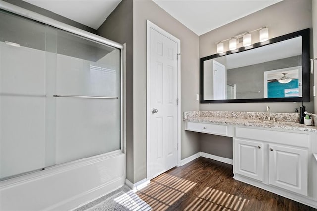 full bath with baseboards, wood finished floors, and vanity