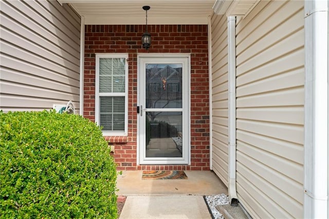 view of exterior entry with brick siding and covered porch