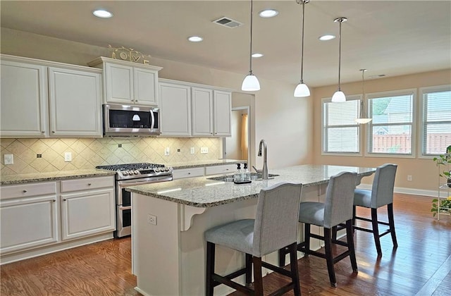 kitchen with appliances with stainless steel finishes, a sink, white cabinetry, dark wood finished floors, and recessed lighting