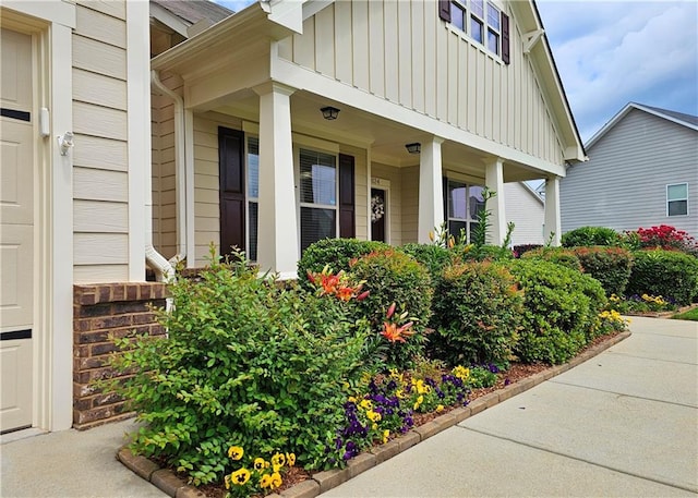 view of exterior entry with board and batten siding and covered porch