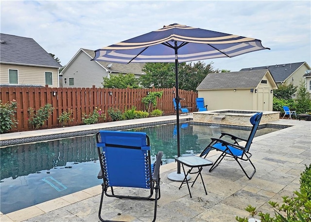 view of swimming pool featuring a fenced backyard, a patio, an outbuilding, and a pool with connected hot tub