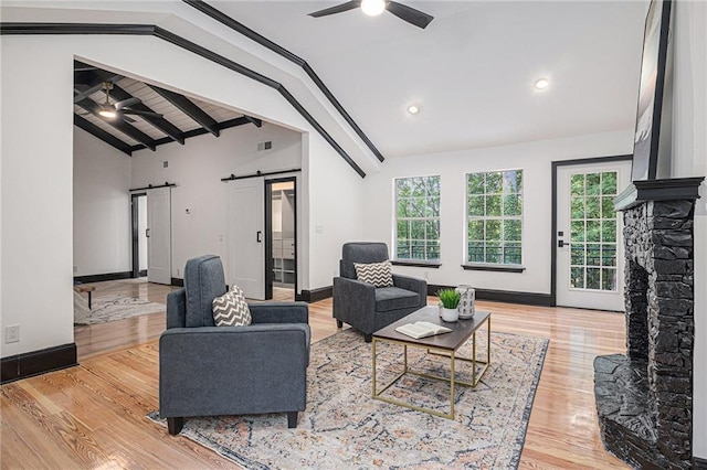 2432 Thompson Mill Rd, Gainesville, GA 30506 - living room featuring a barn door, ceiling fan, plenty of natural light, wood finished floors, and beam ceiling