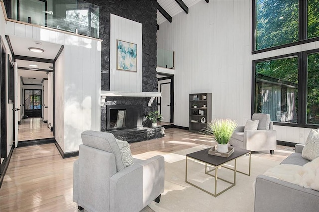 2432 Thompson Mill Rd, Gainesville, GA 30506 - living room featuring high vaulted ceiling, a stone fireplace, wood finished floors, beam ceiling, and baseboards