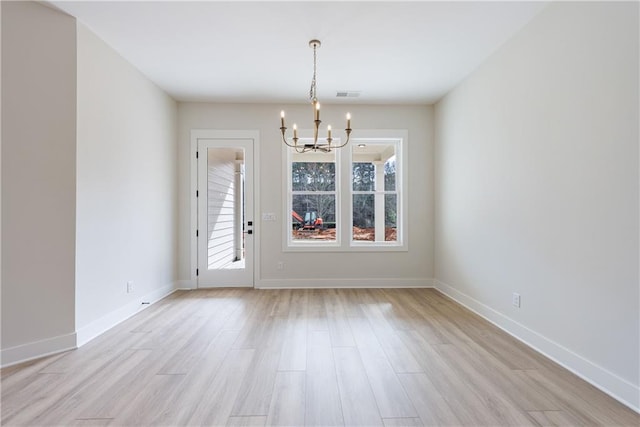 unfurnished dining area with plenty of natural light, an inviting chandelier, light wood-style floors, and visible vents