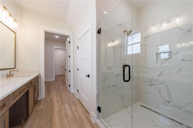 full bath featuring wood finished floors, a marble finish shower, and vanity