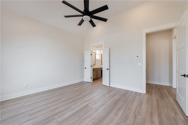 unfurnished bedroom with light wood finished floors, high vaulted ceiling, connected bathroom, and baseboards