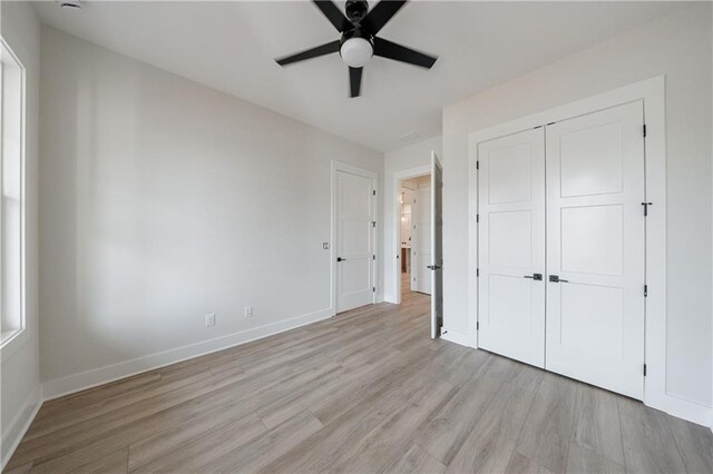 unfurnished bedroom featuring a closet, light wood finished floors, a ceiling fan, and baseboards