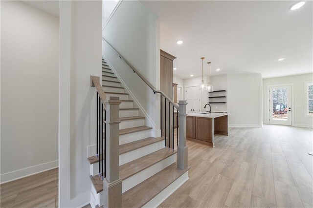 stairway with wood finished floors, recessed lighting, and baseboards