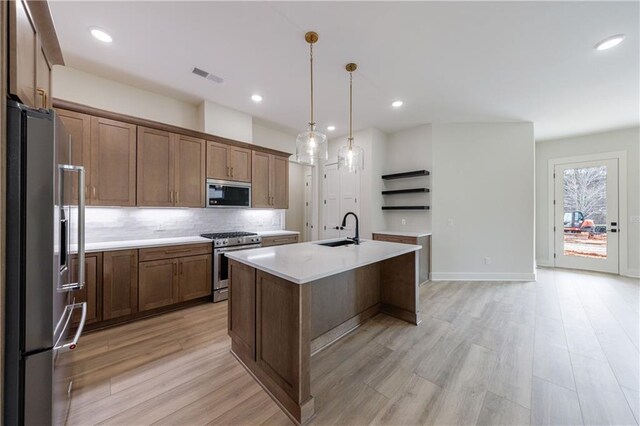 kitchen featuring a sink, stainless steel appliances, light wood-type flooring, visible vents, and light countertops