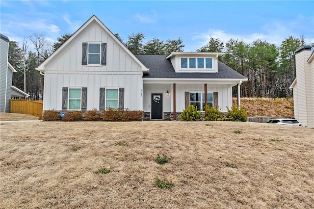 modern inspired farmhouse with board and batten siding, roof with shingles, fence, and a front lawn