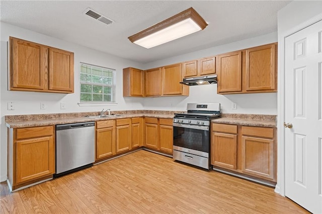 kitchen with stainless steel appliances, sink, and light hardwood / wood-style flooring