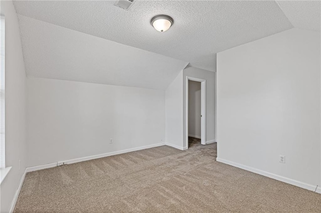 additional living space featuring lofted ceiling, light colored carpet, and a textured ceiling