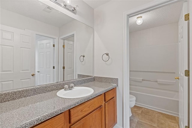 bathroom with vanity, toilet, and a textured ceiling