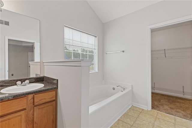 bathroom with lofted ceiling, vanity, and a bathtub