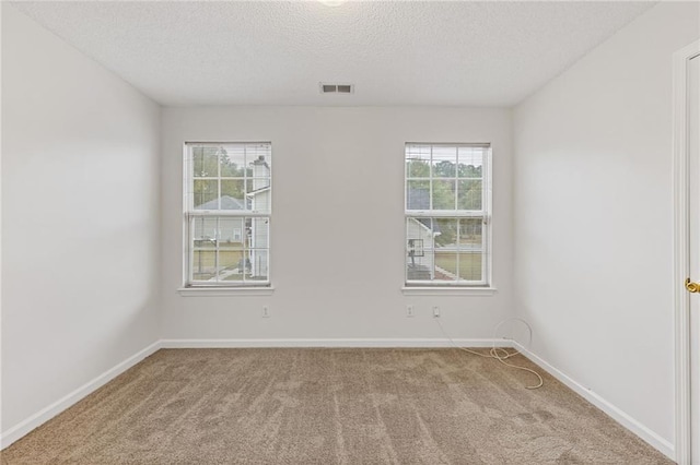 empty room with light carpet and a textured ceiling