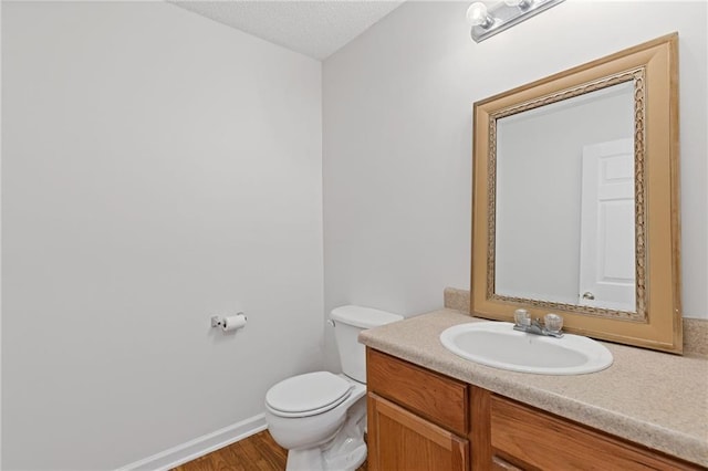 bathroom featuring vanity, hardwood / wood-style floors, a textured ceiling, and toilet