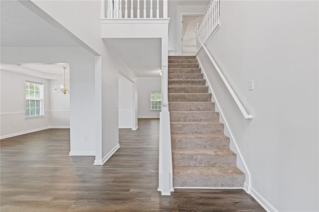 stairway with an inviting chandelier and hardwood / wood-style floors