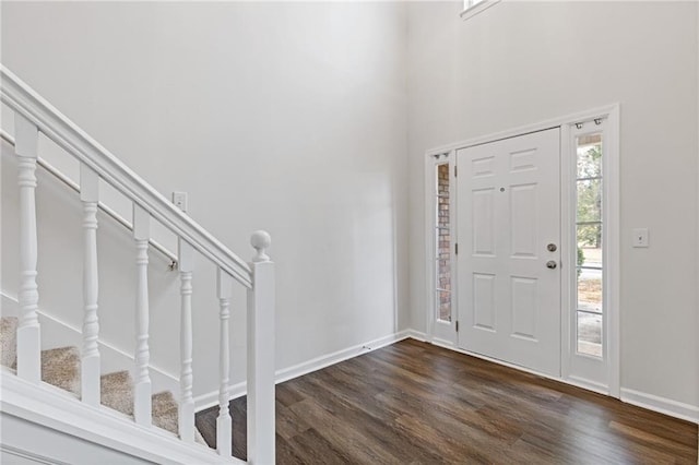 entryway with dark wood-type flooring and a towering ceiling