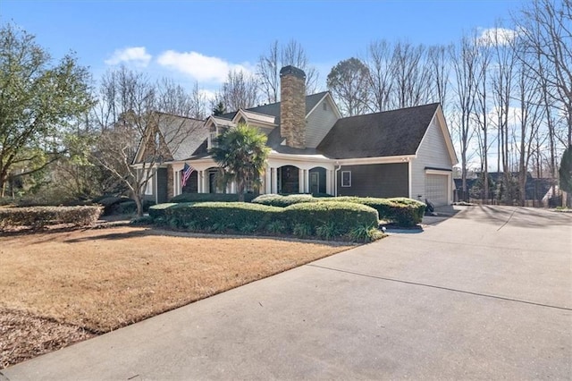 view of front of home featuring concrete driveway, a garage, a front yard, and a chimney