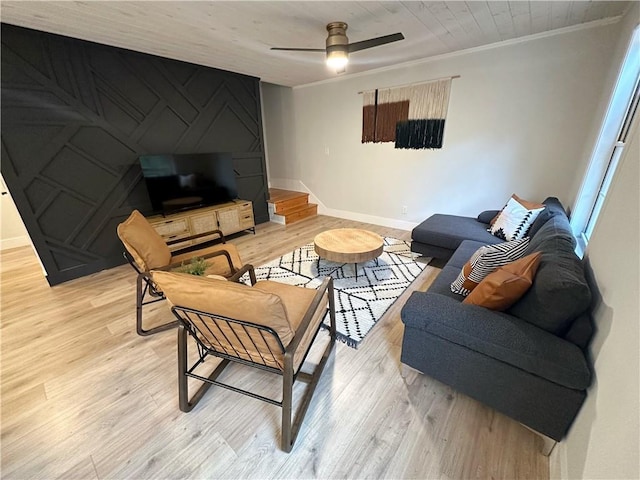 living room with stairway, baseboards, ceiling fan, crown molding, and light wood-type flooring