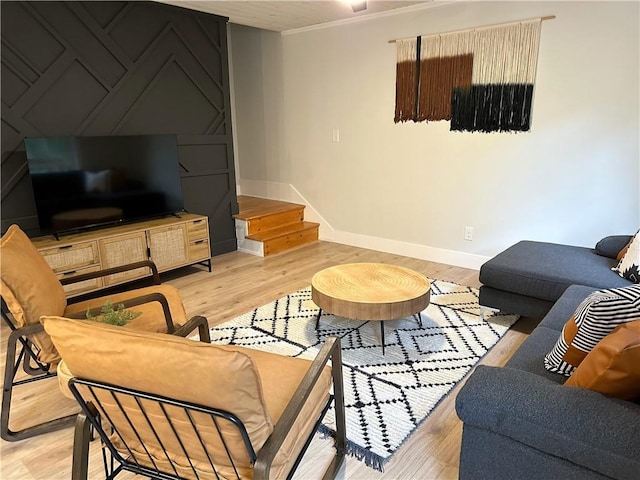 living area with crown molding, stairway, baseboards, and light wood-type flooring