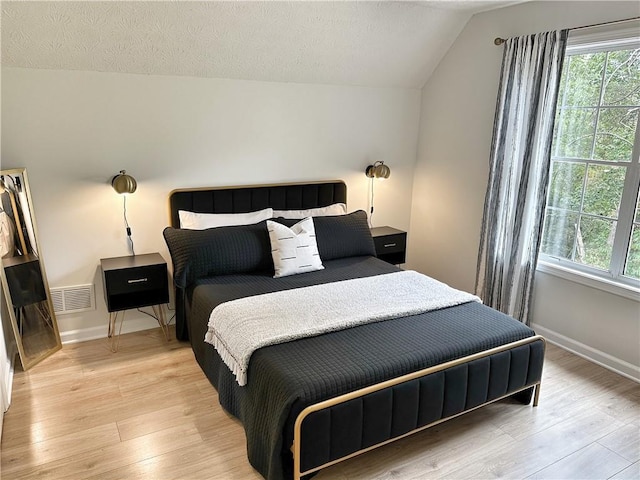 bedroom with a textured ceiling, multiple windows, visible vents, and light wood-type flooring