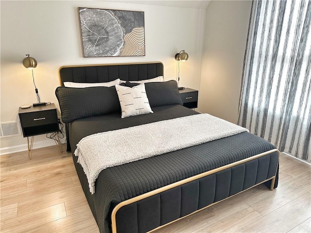 bedroom with visible vents, baseboards, and wood finished floors