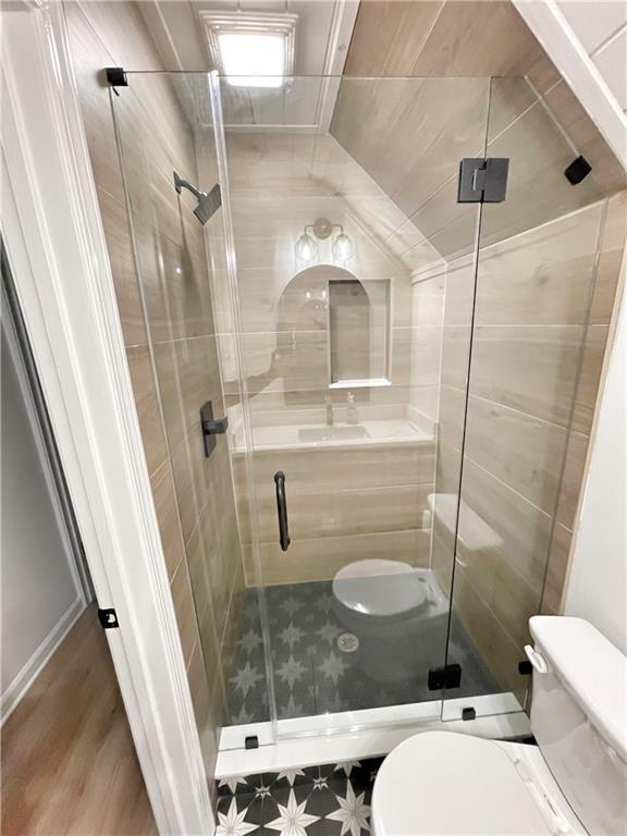 full bathroom featuring wood finished floors, toilet, and a stall shower