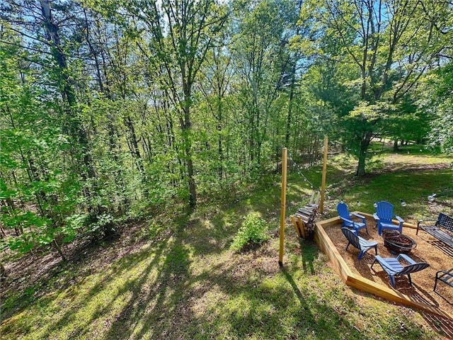 view of yard with a fire pit and a view of trees