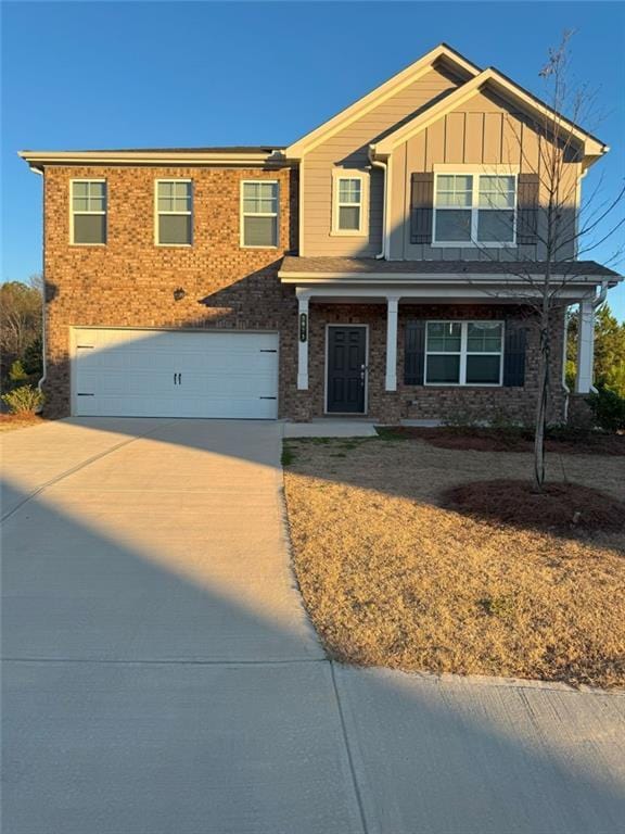 craftsman-style home featuring a garage, concrete driveway, brick siding, and board and batten siding