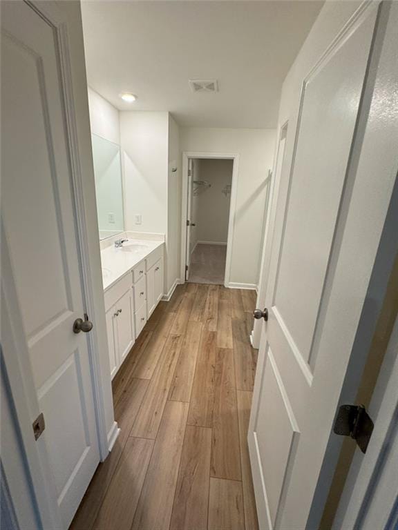 bathroom featuring baseboards, visible vents, wood finished floors, a spacious closet, and vanity