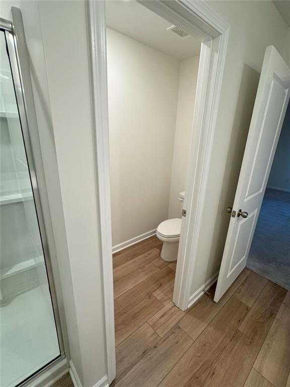 bathroom featuring visible vents, a stall shower, wood finished floors, and toilet